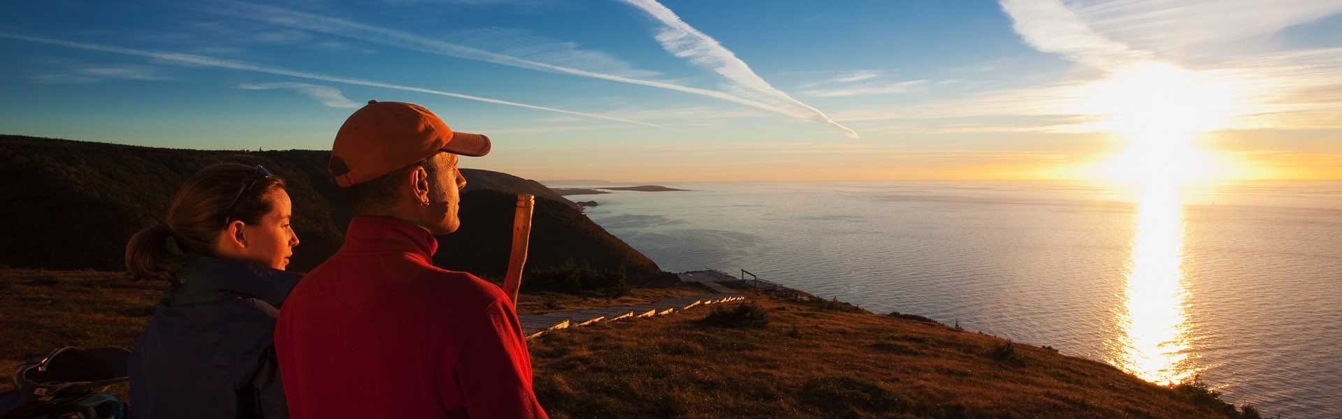 Two hikers stop to watch the sunset over the ocean