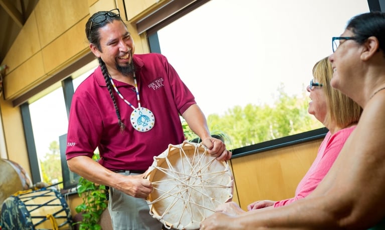 A tour guide shows tourists a traditional Mi'kmaq drum