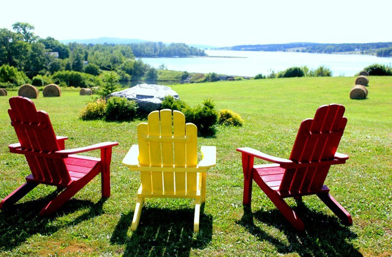 Three adirondack chairs overlooking the ocean