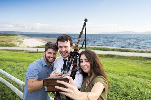 A couple snap a selfie with a bagpipe player