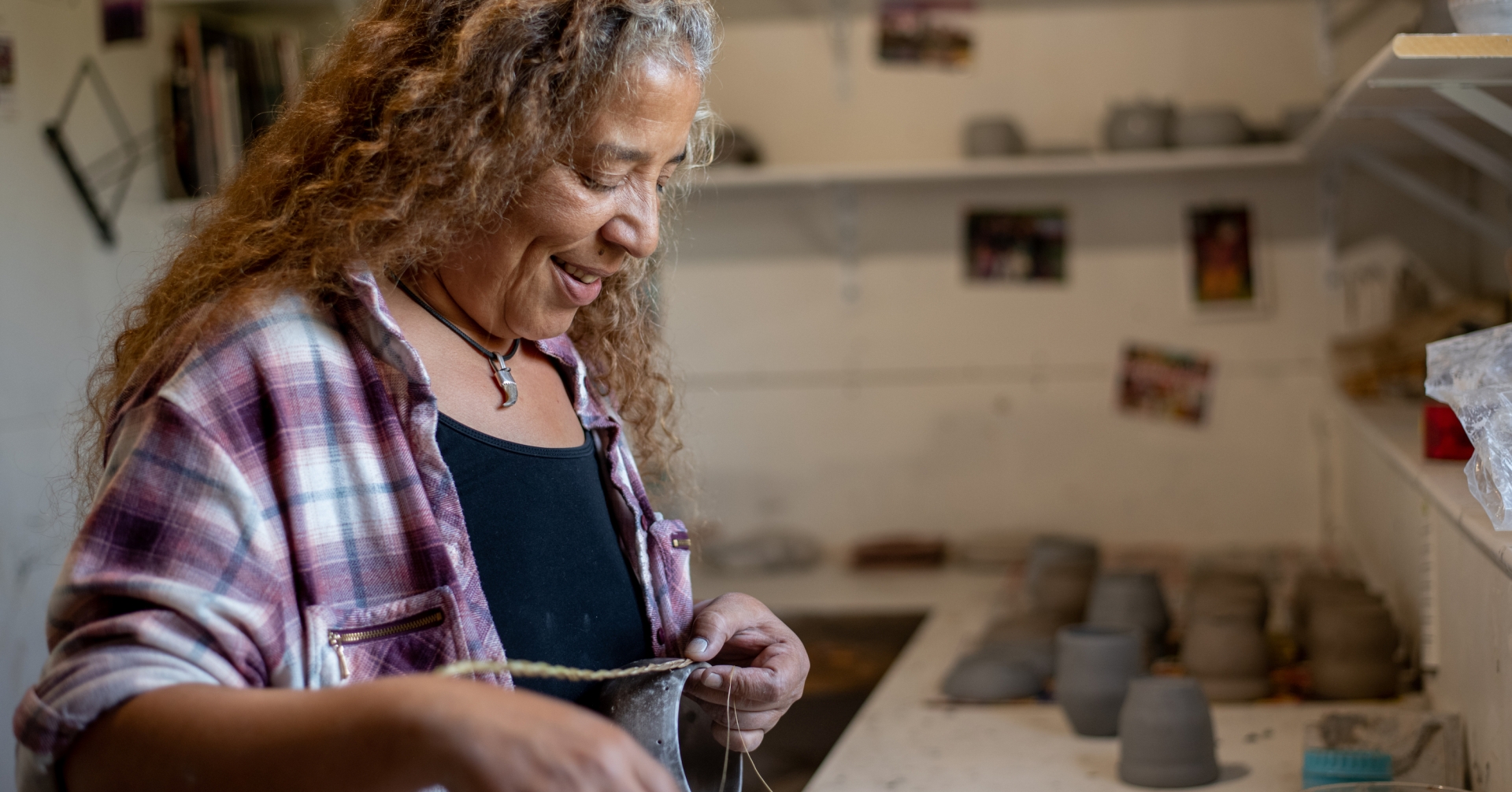 Women works on clay pieces at pottery studio